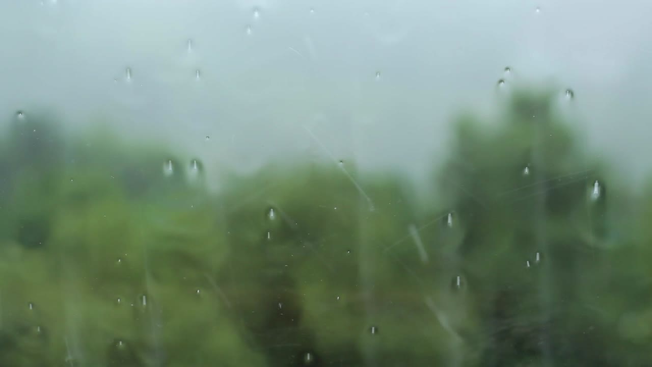 Rain drop on a window inside a house or a car and with green nature in the background