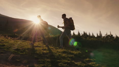 a pair of travelers climbs a mountain silhouettes in the rays of the setting sun