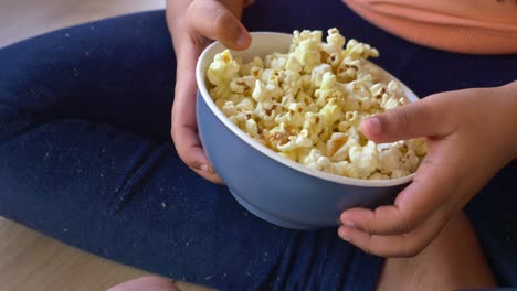 a young girl enjoys a bowl of popcorn