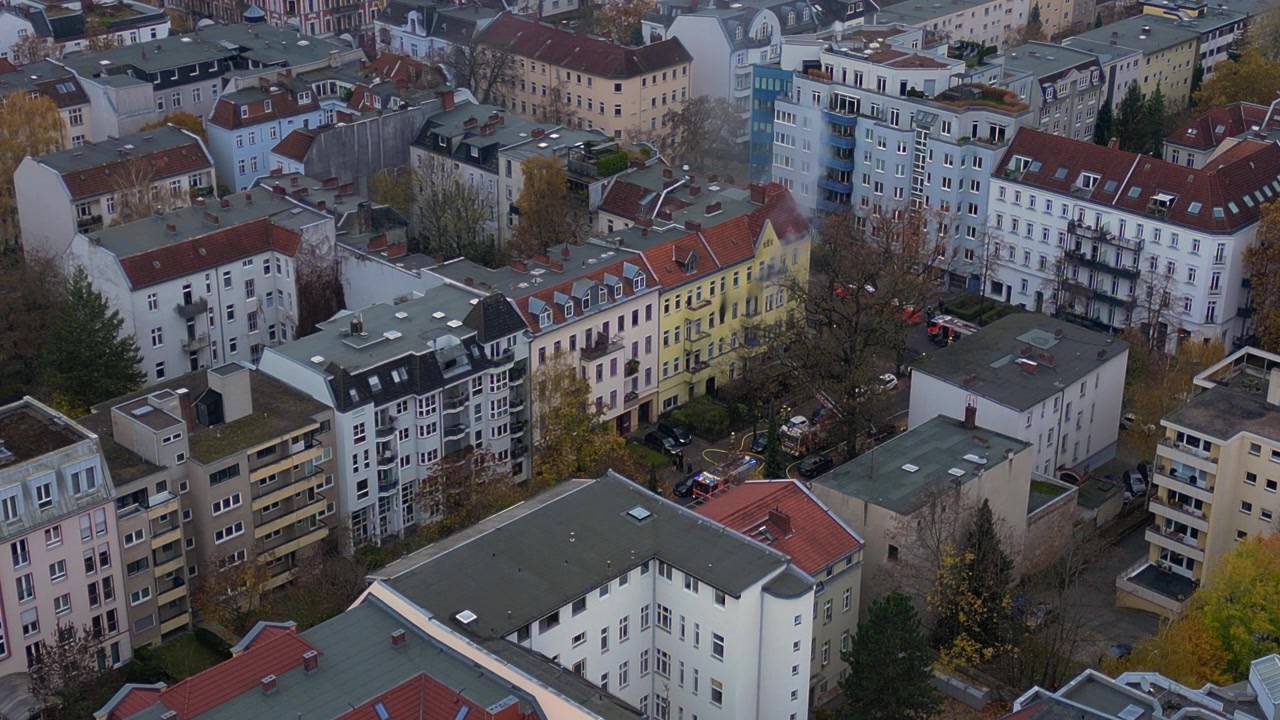 Feuerwehrleute löschen einen Brand in einem Wohngebäude in Berlin, Deutschland, was die Bedeutung von Rettungsdiensten unterstreicht. Einzigartige Luftaufnahme: statische Drohne im Schwebeflug