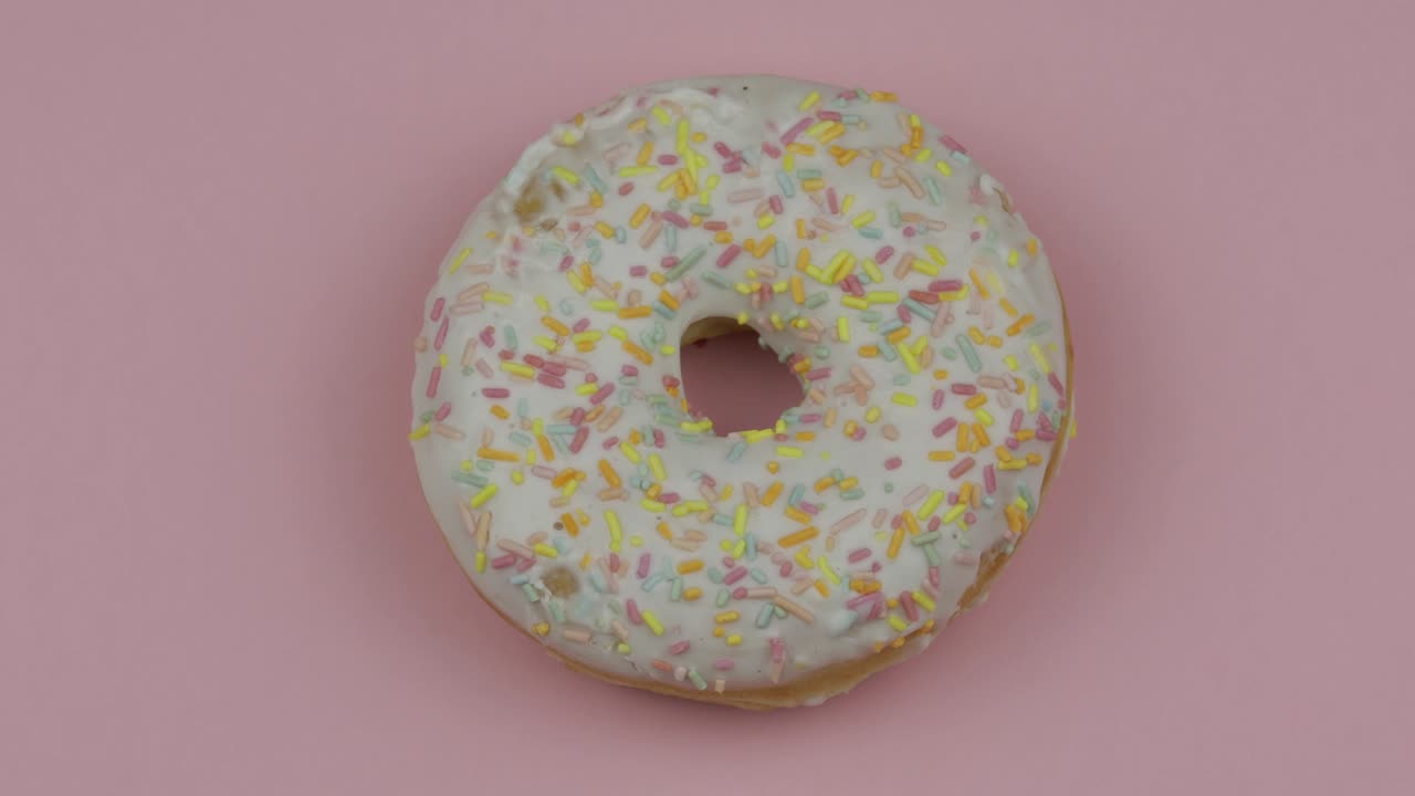 donut dulce girando sobre un fondo rosado. vista superior. donut sabroso y fresco rociado