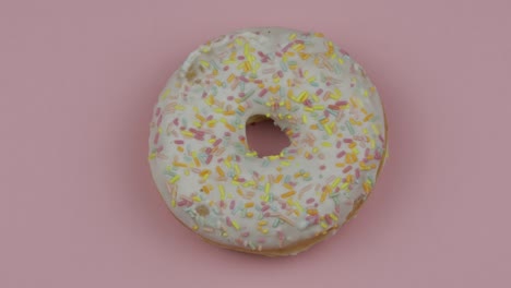 donut dulce girando sobre un fondo rosado. vista superior. donut sabroso y fresco rociado