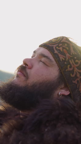 plump bearded man plays shamanic drum dancing in religious ecstasy closeup. worship old nature gods at highland. ritual music sounds
