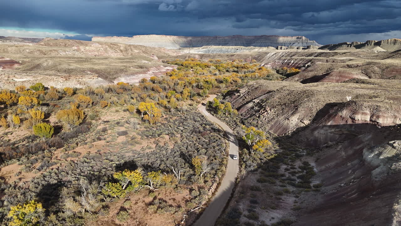 Tracking Drone Shot of White Car on Desert Road and Yellow Foliage in Autumn Season in Utah USA