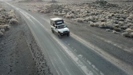 camión conduciendo en un camino de tierra en el desierto, tiro de seguimiento aéreo ancho