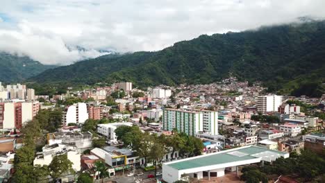 aerial-perspective-of-captivating-cityscape-of-Ibagué,-revealing-its-vibrant-streets-and-huge-mountains-in-background,-bustling-neighborhoods,-and-enchanting-landmarks-from-a-unique-viewpoint