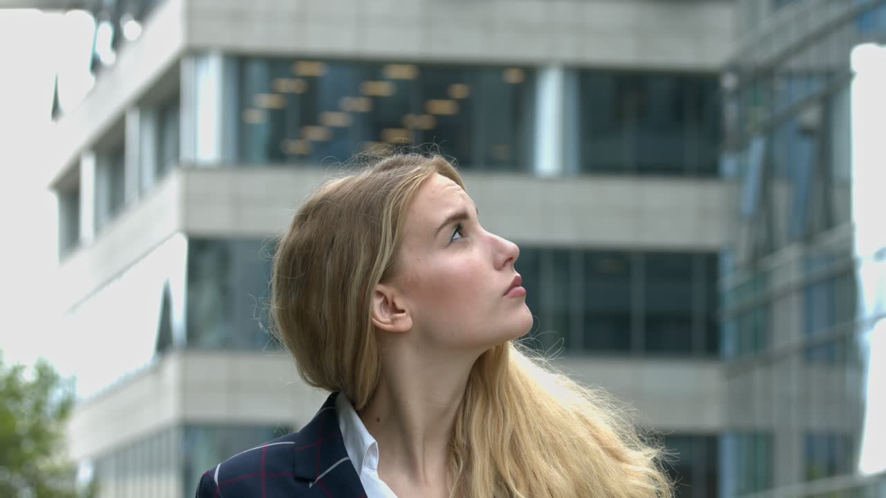 Young Businesswoman Looking Up at Modern City Building