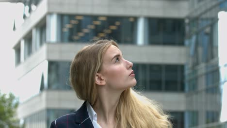 young businesswoman looking up at modern city building