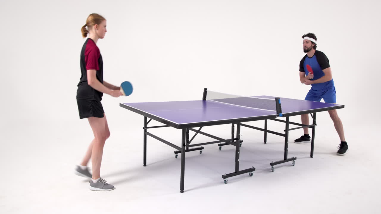 Playing table tennis, man and woman competing in intense match indoors