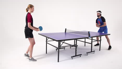 playing table tennis, man and woman competing in intense match indoors