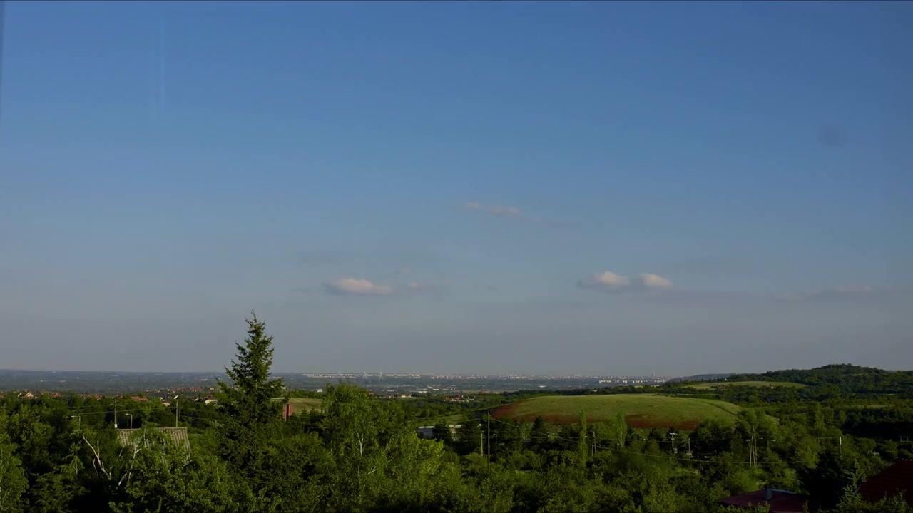 Time-lapse clouds moving and blue sky over green hills