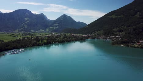 drone, toma aérea del puerto de weesen en suiza con una fuente de agua rodeada de alpes suizos