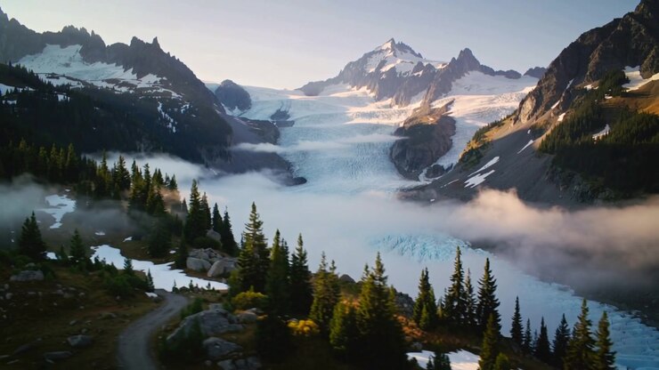 Drone in volo che si muove e panoramica su una valle alpina, con la luce solare che dirada la nebbia, rivelando un sentiero sulla cima di un ghiacciaio.