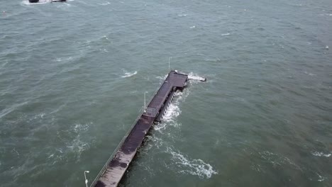 Drone-aerial-over-ocean-Melbourne-wavy-windy-cloudy-day-with-waves-crashing-on-pier