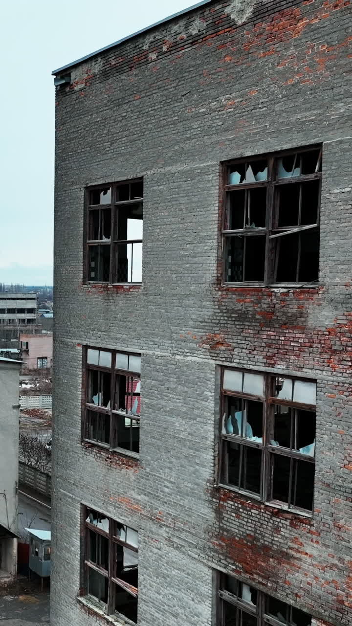 Damaged ruins of past big plant. Forlorn wrecked emptied buildings with no windows and old brick walls. Blue clear sky at the background. Vertical video