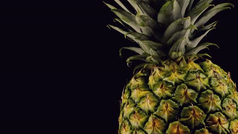 Ananas-Dreht-Sich-Langsam,-Während-Ein-Wassertropfen-Auf-Die-Goldene-Haut-Auf-Schwarzem-Hintergrund-Tropft