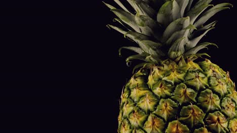 la piña gira lentamente mientras la gota de agua gotea sobre la piel dorada sobre un fondo negro