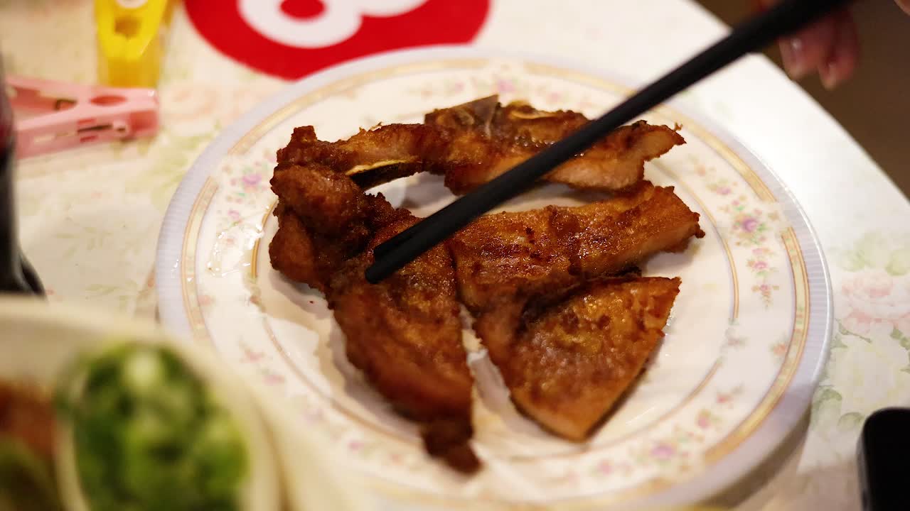 palillos de comer recogiendo carne de cerdo frita de un plato