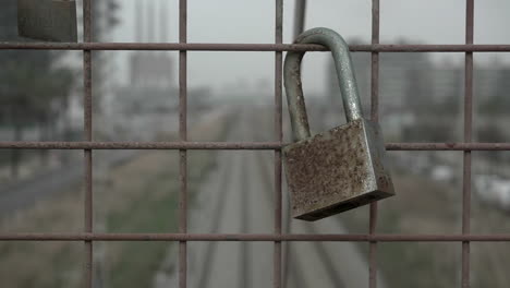 old rusty love lock hanging on the iron fence of a train bridge