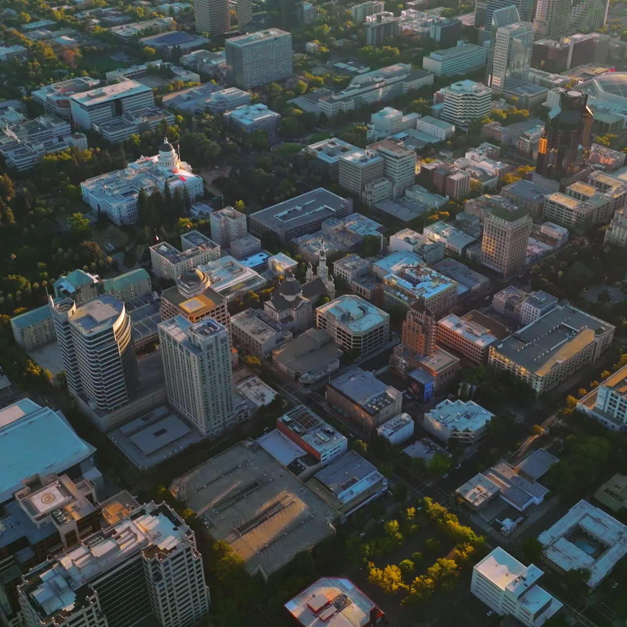 Sacramento city architecture full of greenery from aerial perspective. Drone footage over the city at sunset