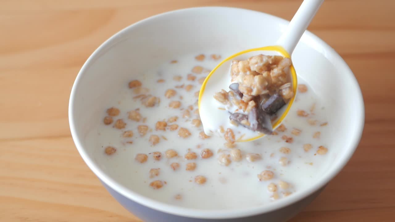 Un cucchiaio che preleva cereali con latte e pezzi di cioccolato da una ciotola