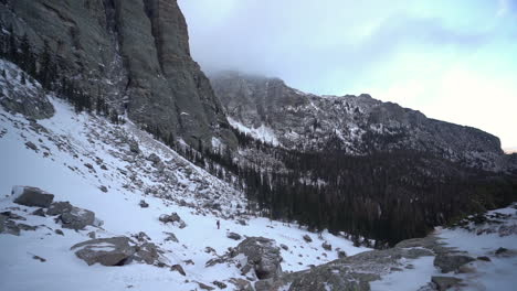 paisaje de montaña de invierno helado y persona solitaria caminando cuesta arriba, cámara lenta