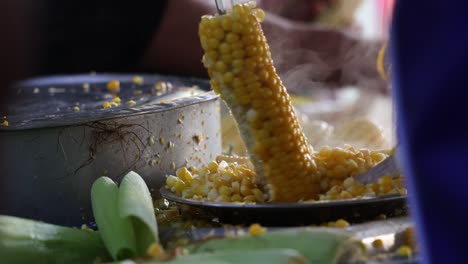 threshing boiled yellow maize corn with knife, hot boiled maize corn