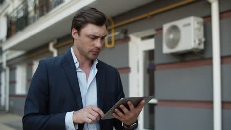Closeup business man using tablet at street. Man working on touchpad outdoors