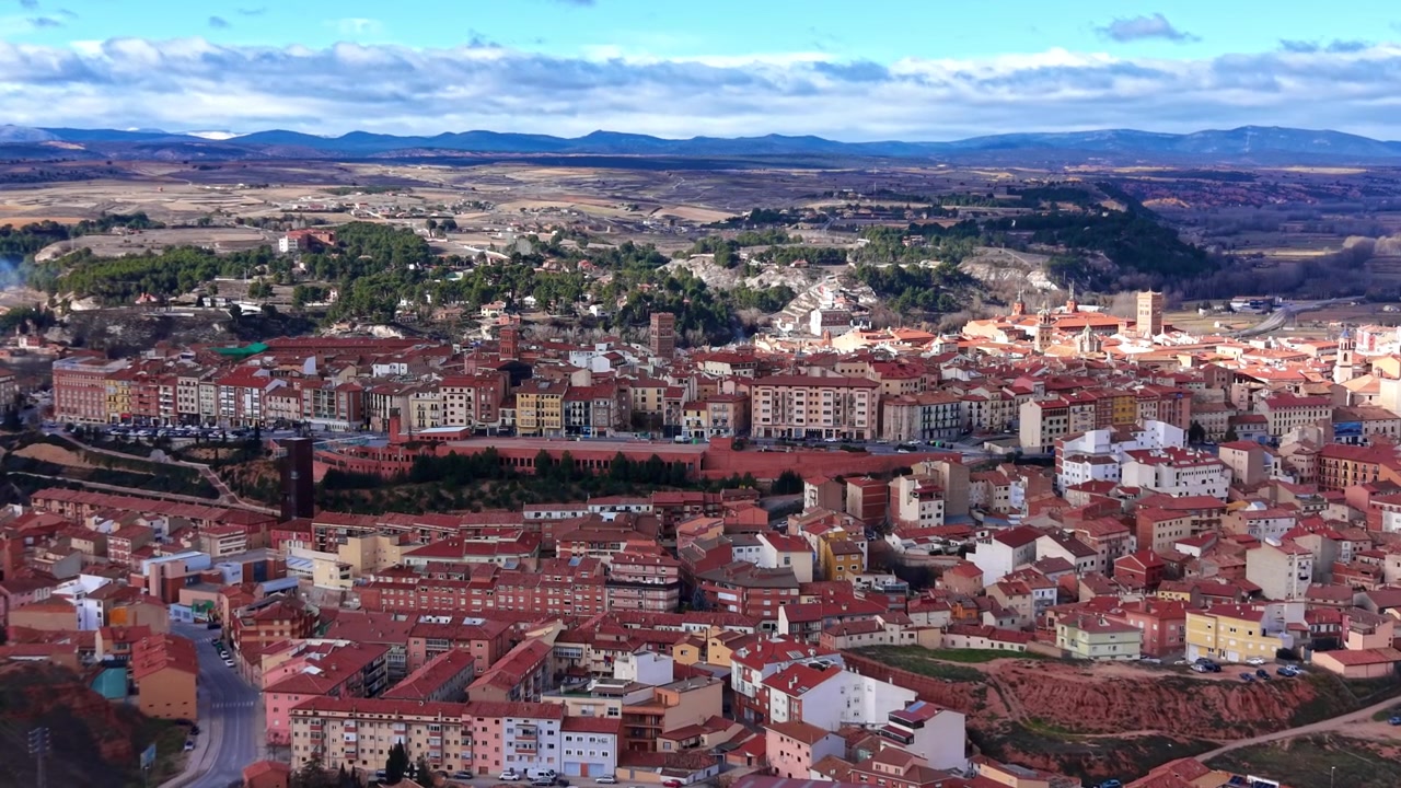 Vista panoramica di Teruel, Spagna, che mostra tetti in terracotta, edifici storici, valli e montagne circostanti sotto un cielo parzialmente nuvoloso