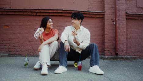 couple eating hot dogs and drinks on a skateboard