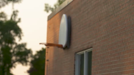 rack focus on a basketball hoop hanging on the red brick wall of a school