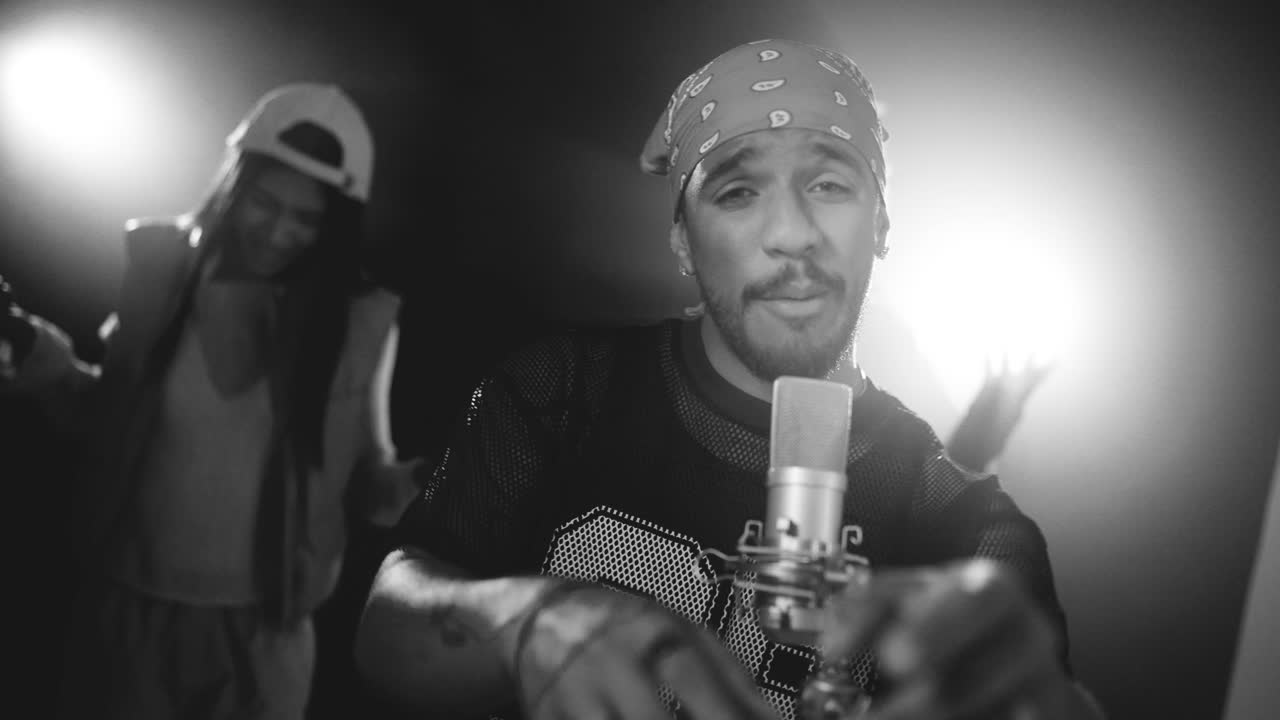 Black and white music video of rapper singing into a microphone