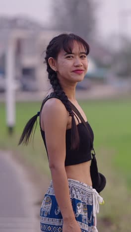a woman with braids wearing a crop top and shorts standing in a field