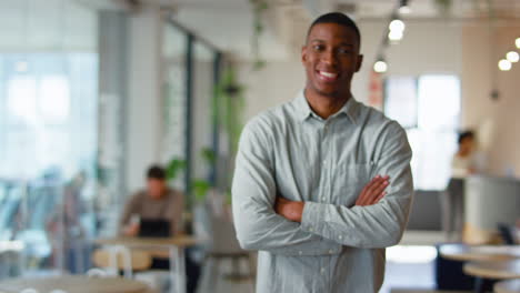 Portrait-Of-Smiling-Businessman-Standing-In-Modern-Open-Plan-Office