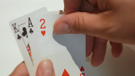 close-up of a card player's hands picking up a random deal of playing cards