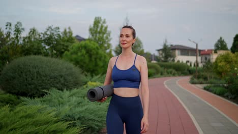 woman walking in park with yoga mat