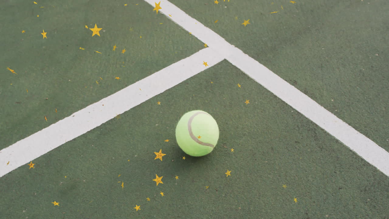 Single tennis ball resting on green court surface, being framed by white lines and golden stars