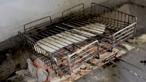 person roasting wrapped sandwich on grill over charcoal