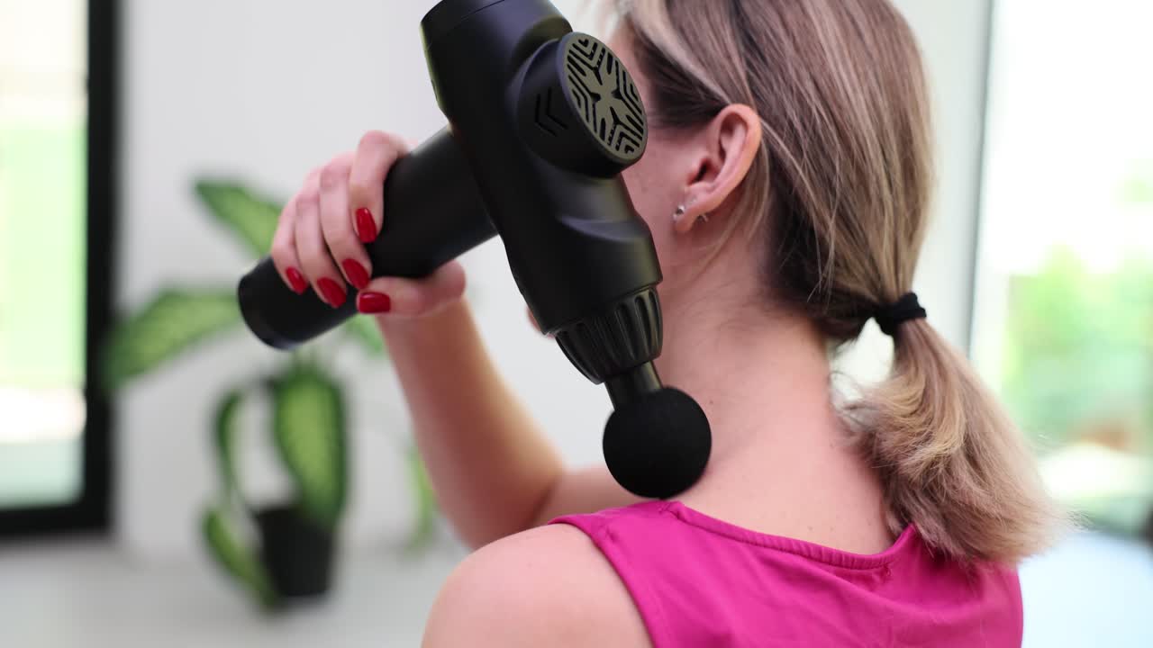 Woman using a massage gun on her back
