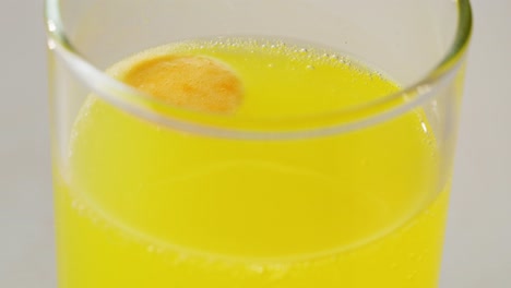 glass of yellow soda with a tablet