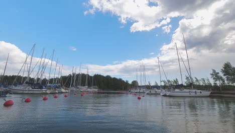 time lapse: cumulus clouds roll by in blue sky over sailboat marina