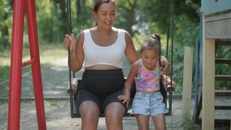 madre y hija embarazadas jugando en el columpio al aire libre