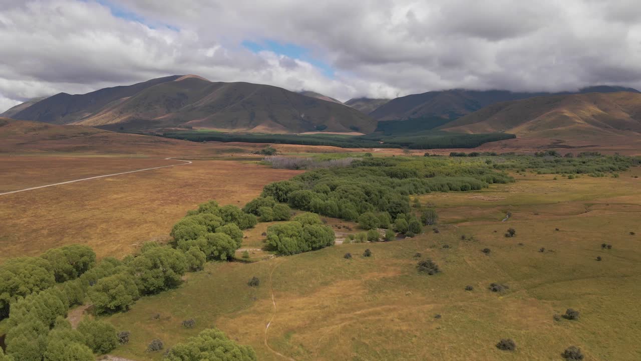 frondosos árboles que crecen a lo largo de un río que sale directamente de las montañas en un vasto paisaje salvaje