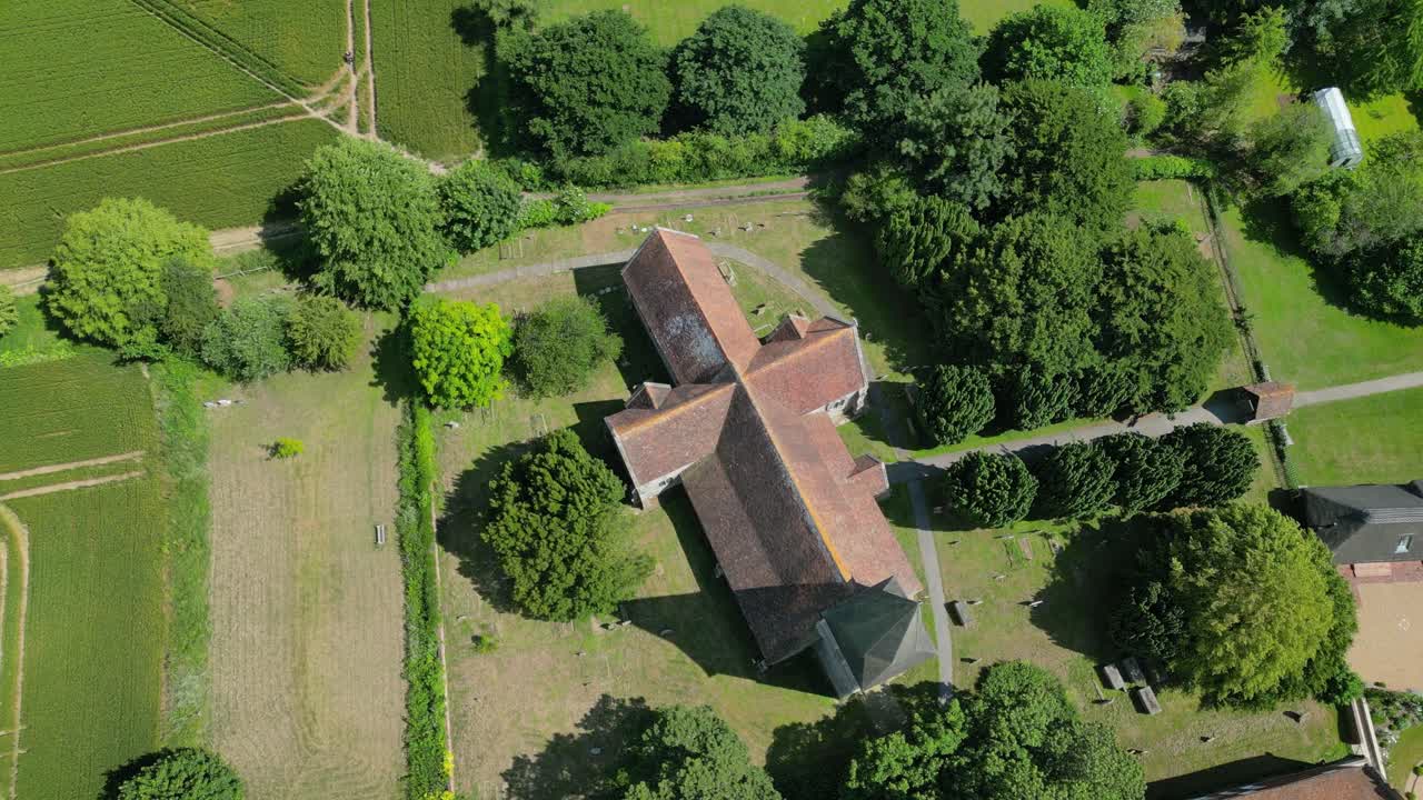 A bird's-eye-view arc-shot of St John the Evangelist church in Ickham, Kent, showing the graveyard and nearby fields