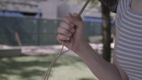 tight shot of woman's hand holding an umbrella while walking through an urban park