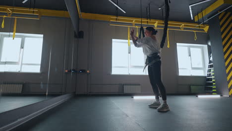 indoor workout with strength training equipment woman is hanging and doing push-up healthy lifestyle