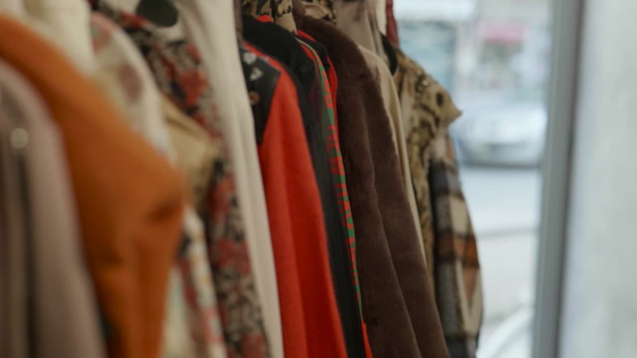 mujer tomando un vestido de un estante de ropa con un movimiento de gimnasia de adelante hacia atrás