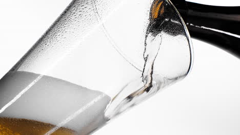 close up background of pouring beer with bubbles and foam in glass low angle side view slow motion