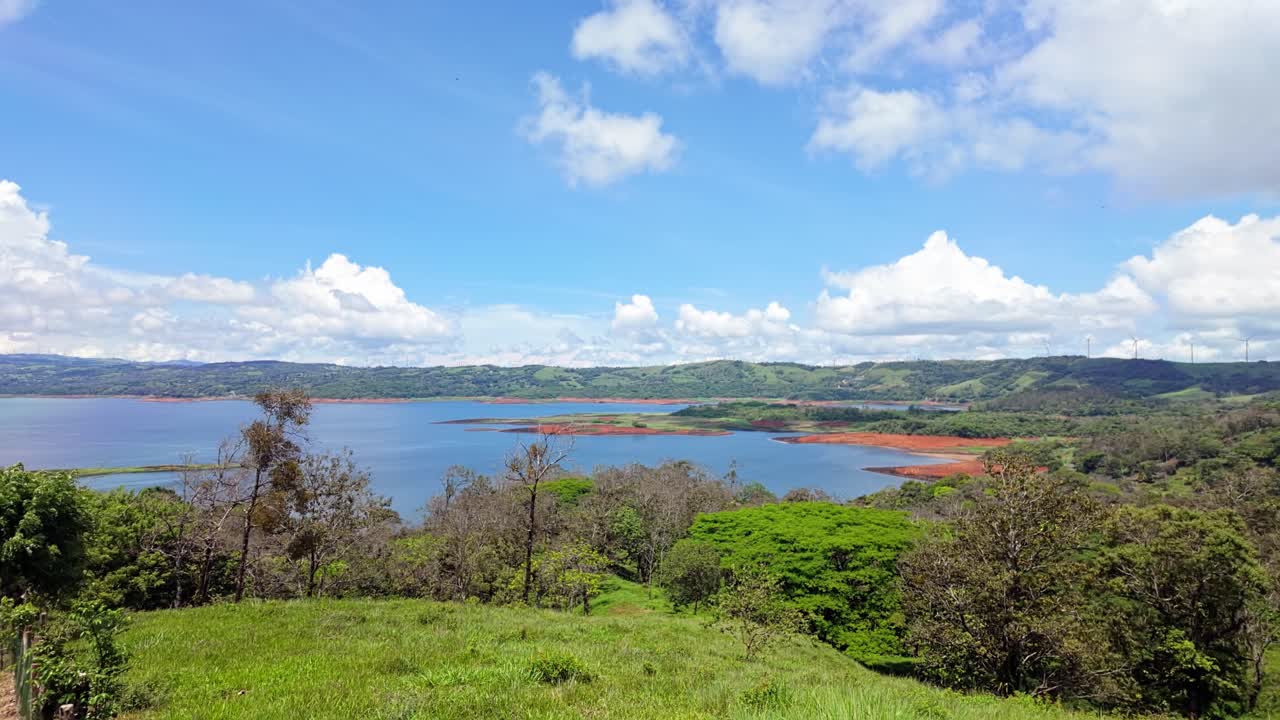 vista del paisaje idílico desde la zona norte del lago arenal con los campos verdes y bosques circundantes en un día soleado con un cielo azul nublado en costa rica