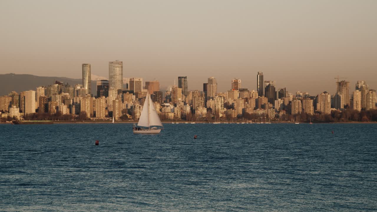 Sail Boat Sailing On The Jericho Beach With Skyscrapers Of Vancouver In The Background In Canada At Dusk. - wide shot